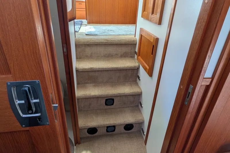 Slide: The Image of Interior stairs of a 2010 Nordic Tug 32, featuring wooden accents and carpeted steps. - 45