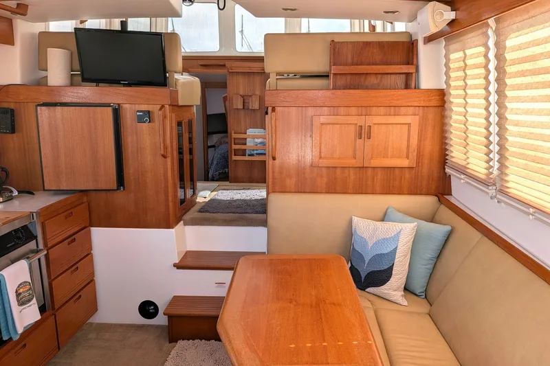 Slide: The Image of Interior of 2010 Nordic Tug 32 with wooden cabinetry, seating area, and TV. - 13