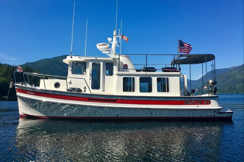 The Image of 2010 Nordic Tug 32 boat on serene lake with mountainous backdrop. - 0