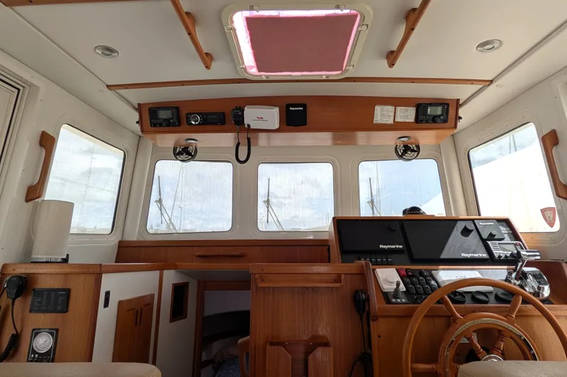 Slide: The Image of Interior of a 2010 Nordic Tug 32 boat, featuring a wooden helm and navigation equipment. - 24