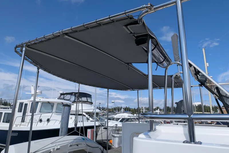 Slide: The Image of Nordic Tug 32 (2010) with canopy, docked at marina under clear blue sky. - 9