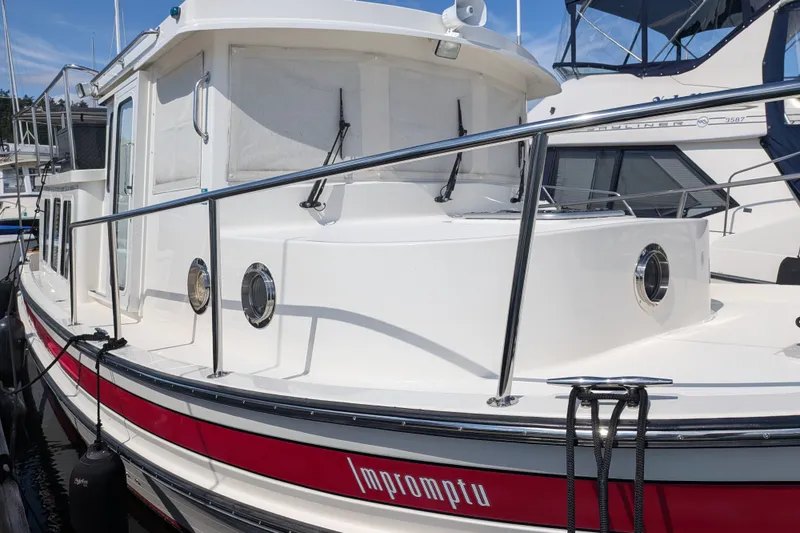 Slide: The Image of 2010 Nordic Tug 32 boat docked, featuring white exterior and red stripe. - 7