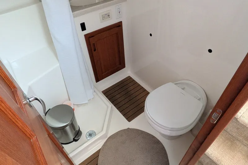 Slide: The Image of Bathroom interior of 2010 Nordic Tug 32, featuring toilet, shower, and wooden cabinetry. - 43