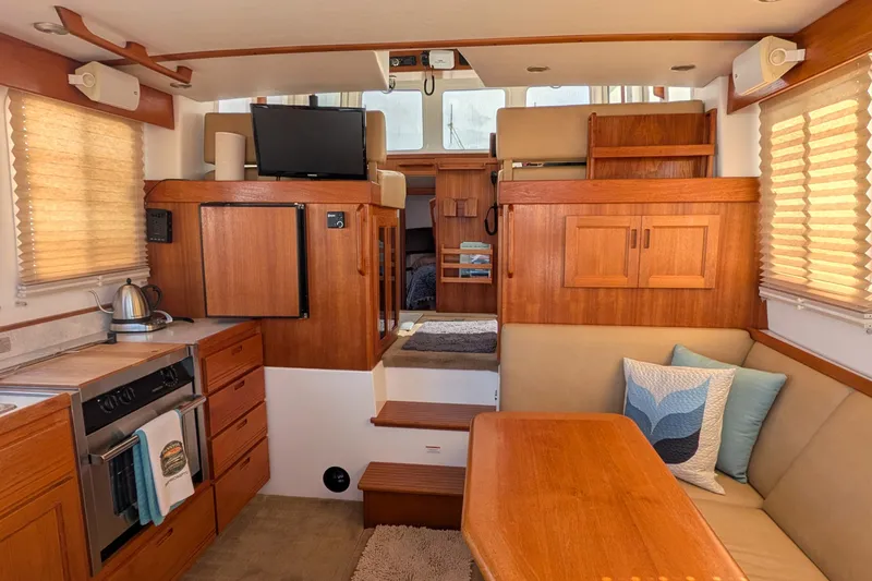 Slide: The Image of Interior of a 2010 Nordic Tug 32, featuring a cozy dining and kitchen area. - 16