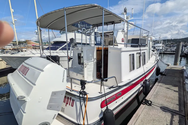 Slide: The Image of 2010 Nordic Tug 32 docked at marina, featuring spacious deck and canopy. - 4
