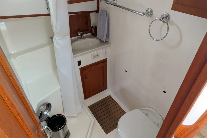 Slide: The Image of Compact bathroom in 2010 Nordic Tug 32, featuring sink, toilet, and shower area. - 41