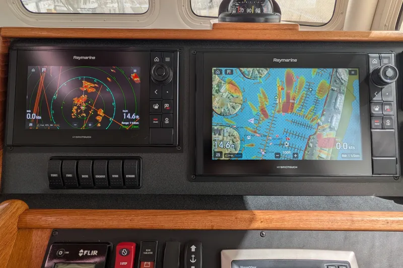 Slide: The Image of Nordic Tug 32 (2010) dashboard with Raymarine navigation displays and control switches. - 30