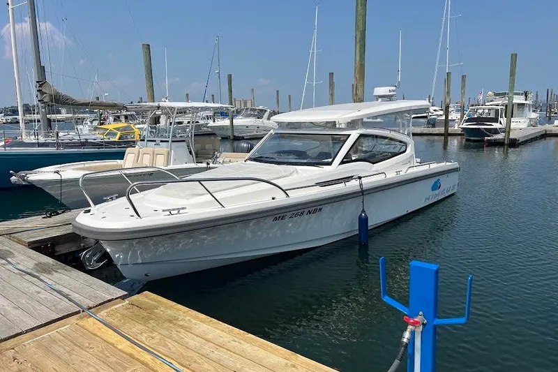 Slide: The Image of 2024 Nimbus Weekender 9 boat docked at a marina, surrounded by other vessels. - 2