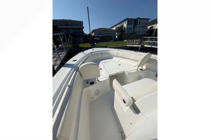 Slide: The Image of 2021 Sea Hunt Gamefish 30FS boat interior with seating, docked near waterfront homes. - 19