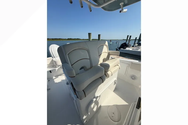 Slide: The Image of 2021 Sea Hunt Gamefish 30FS boat interior with cushioned seating, docked by the water. - 14
