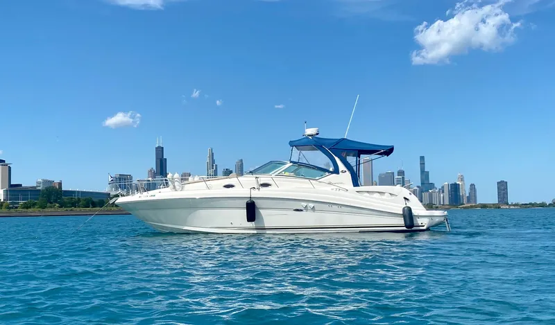 The Image of A 2003 Sea Ray 340 Sundancer on calm water with a city skyline in the background. - 0
