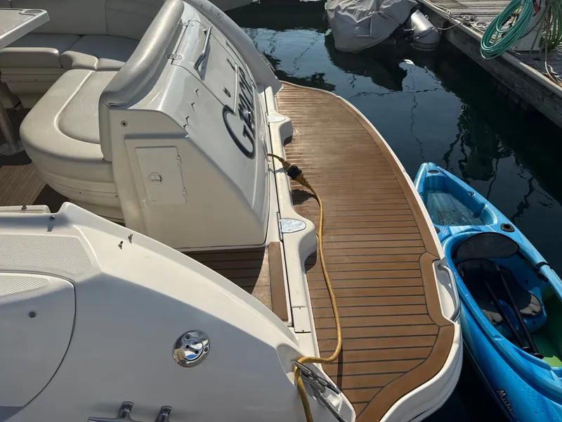 Slide: The Image of The image shows the stern of a 2003 Sea Ray 340 Sundancer. It is docked next to a blue kayak. - 4