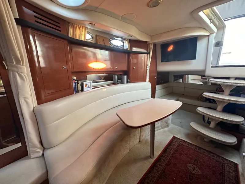 Slide: The Image of Interior of a 2003 Sea Ray 340 Sundancer with curved sofa, table, and TV. - 21