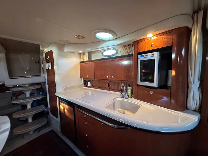 Slide: The Image of The interior of a 2003 Sea Ray 340 Sundancer features an elegant kitchen with wooden cabinets and a sink. - 17