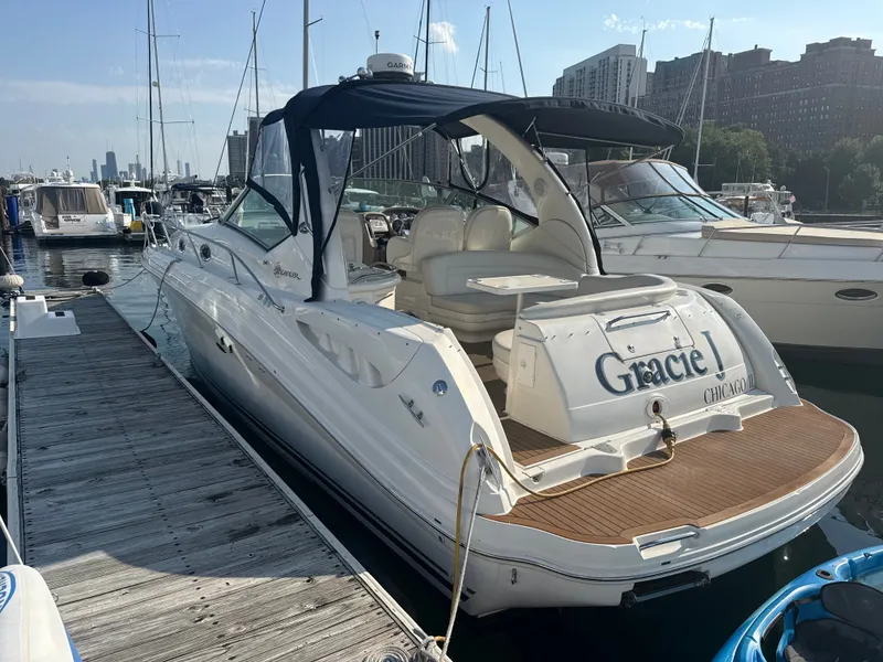 Slide: The Image of A 2003 Sea Ray 340 Sundancer docked. It features a blue canopy and spacious seating area. - 1