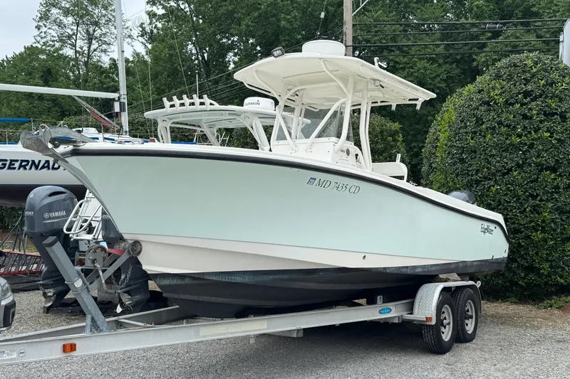 The Image of 2007 Edgewater 245CC boat on trailer, parked outdoors with trees in background. - 0