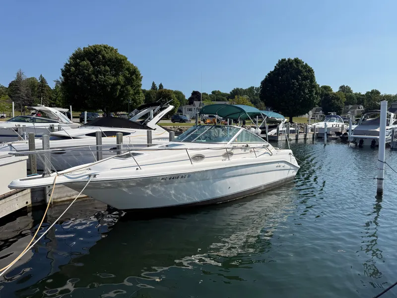 Slide: The Image of A white boat docked at a marina, surrounded by other boats and trees in the background. - 16