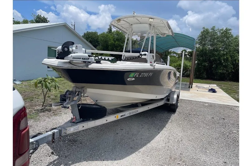 The Image of A 2015 NauticStar 231 Coastal boat on a trailer, parked on a gravel driveway. - 1