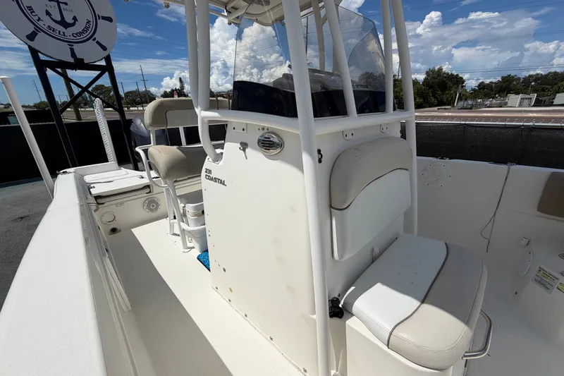 Slide: The Image of 2015 NauticStar 231 Coastal boat interior with seating and console, under a clear blue sky. - 56