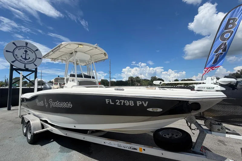 The Image of 2015 NauticStar 231 Coastal boat on trailer, displayed outdoors under blue sky. - 0