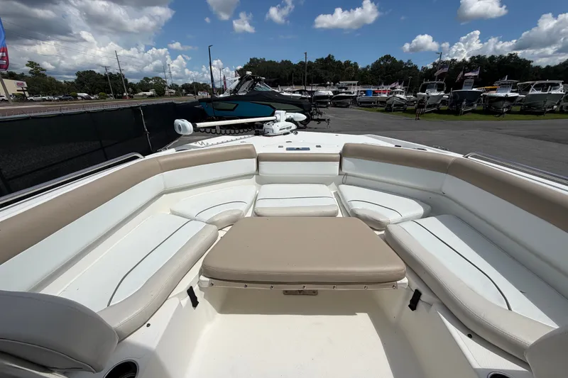Slide: The Image of 2015 NauticStar 231 Coastal boat interior with cushioned seating under a partly cloudy sky. - 43