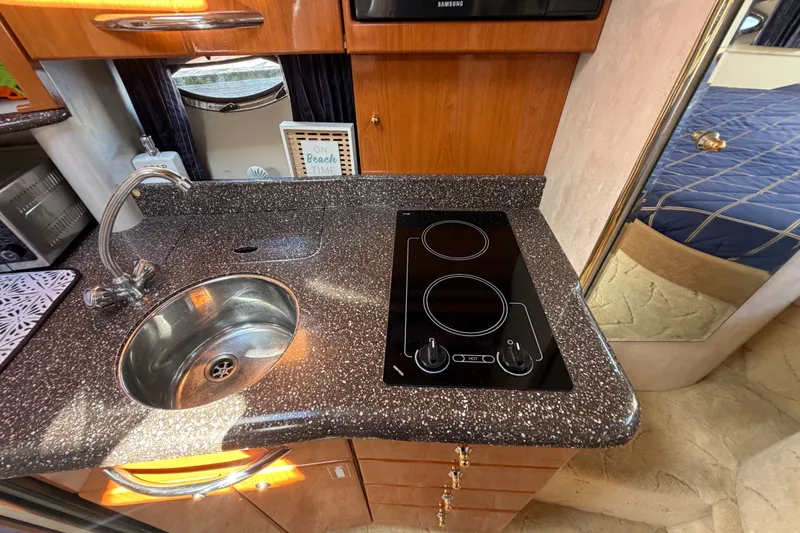 Slide: The Image of Compact kitchen area in a 2003 Formula 37 Performance Cruiser with sink and electric cooktop. - 32
