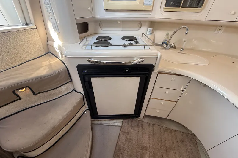 Slide: The Image of Interior of 1996 Sea Ray Sundancer 370, featuring compact kitchen with stove, sink, and fridge. - 36