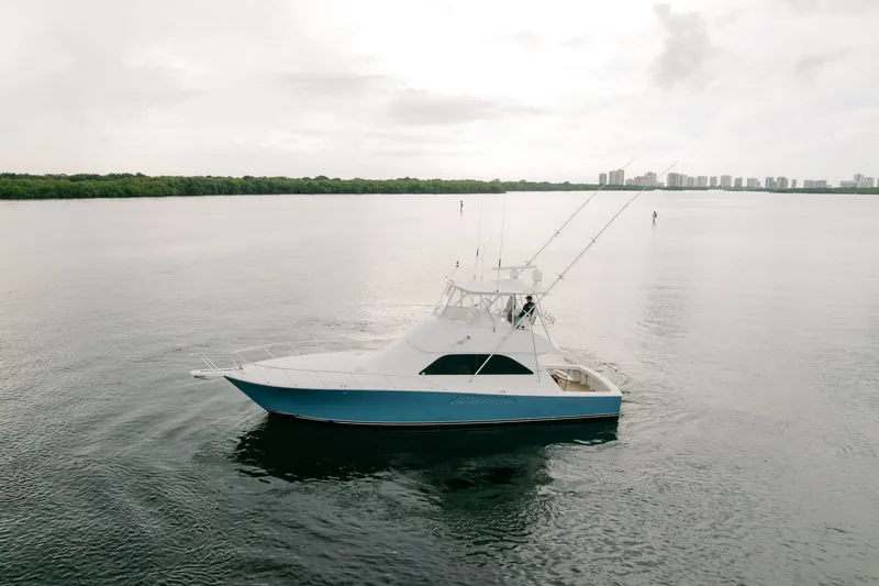 The Image of 2003 Viking 48 Convertible yacht cruising on calm waters with city skyline in background. - 1