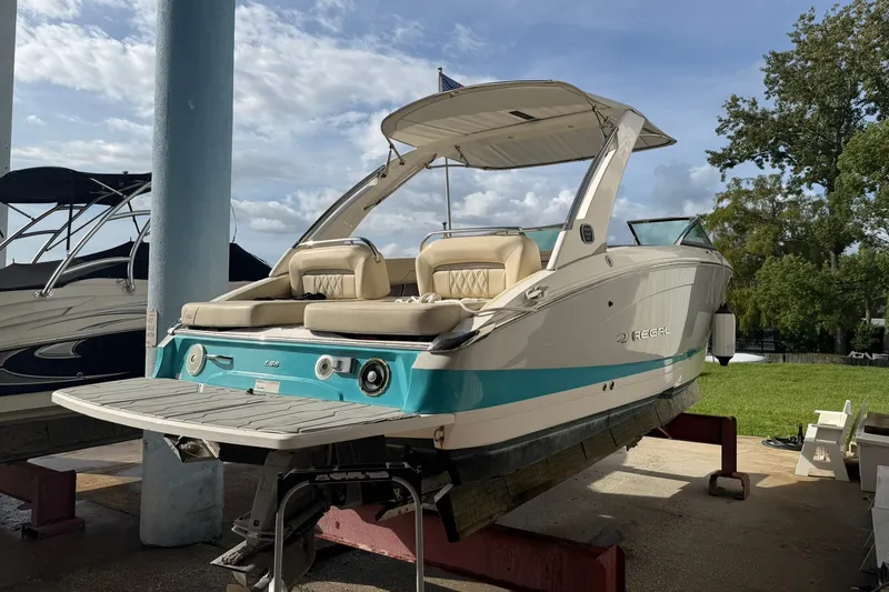 The Image of 2019 Regal LS6 boat with teal accents on a lift, under a clear sky. - 0