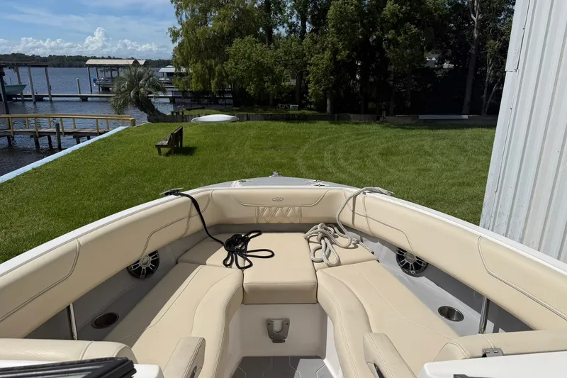 Slide: The Image of 2019 Regal LS6 boat interior with beige seating, dockside view, and lush greenery. - 13