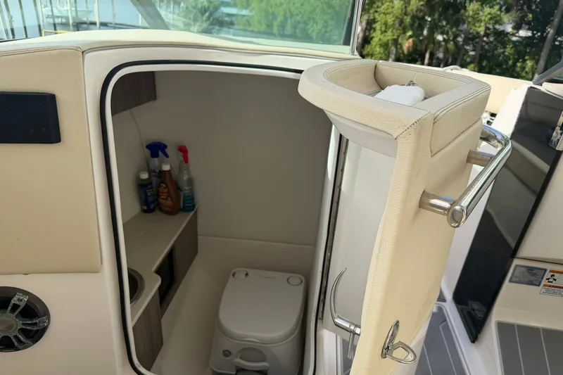 Slide: The Image of 2019 Regal LS6 boat interior with compact toilet and cleaning supplies. - 15