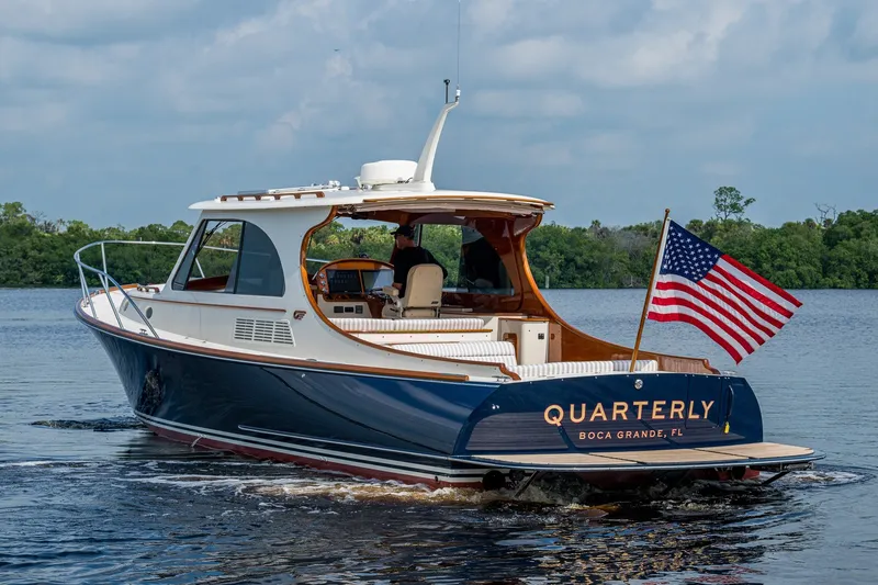 Slide: The Image of 2022 Hinckley Picnic Boat 40 cruising with American flag, named "Quarterly," in scenic waters. - 1