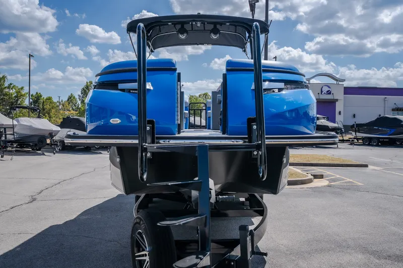 Slide: The Image of 2025 Montara 25 Surf Boss boat on trailer, vibrant blue, parked outdoors under cloudy sky. - 14
