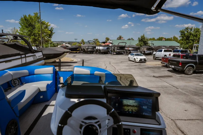 Slide: The Image of 2025 Montara 25 Surf Boss boat interior with blue seating, parked in a marina lot. - 44