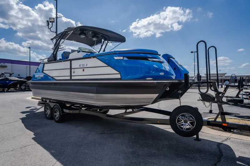 Slide: The Image of 2025 Montara 25 Surf Boss boat on trailer under blue sky. - 13