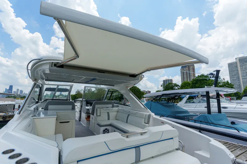 Slide: The Image of 2023 Regal LS36 yacht with open canopy, docked in a marina under a blue sky. - 40