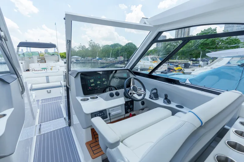 Slide: The Image of 2023 Regal LS36 boat cockpit with modern steering and dashboard, docked in a marina. - 26