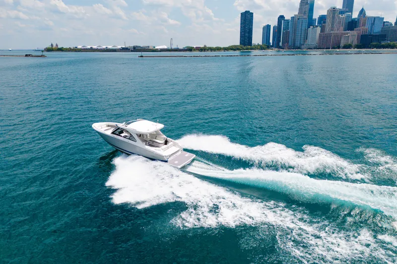 Slide: The Image of 2023 Regal LS36 boat cruising on blue water near city skyline. - 13