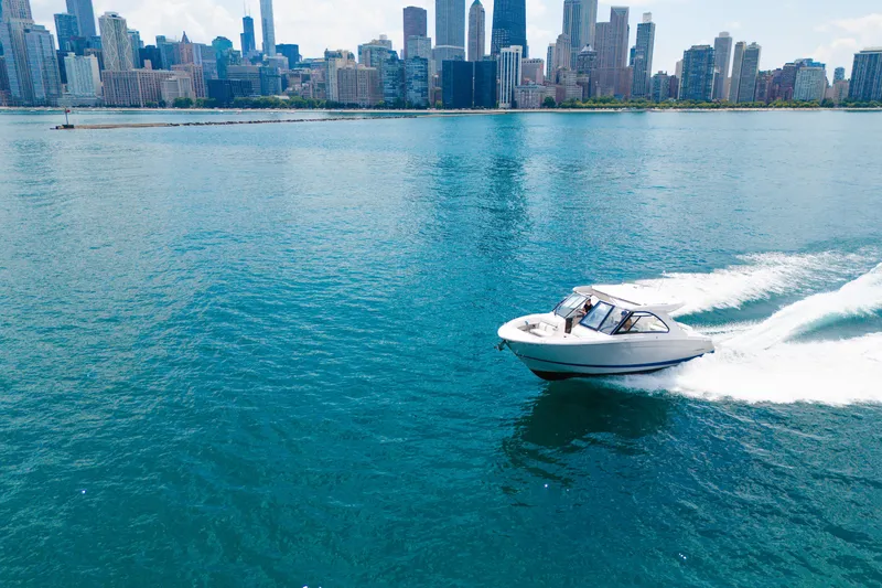 Slide: The Image of 2023 Regal LS36 boat cruising on blue water with city skyline backdrop. - 17