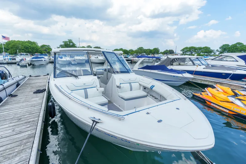 Slide: The Image of 2023 Regal LS36 boat docked at marina, surrounded by other boats and jet skis. - 33