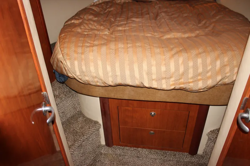 Slide: The Image of Cozy cabin interior of 2006 Sea Ray 40 Sundancer with striped bedding and wooden storage. - 30