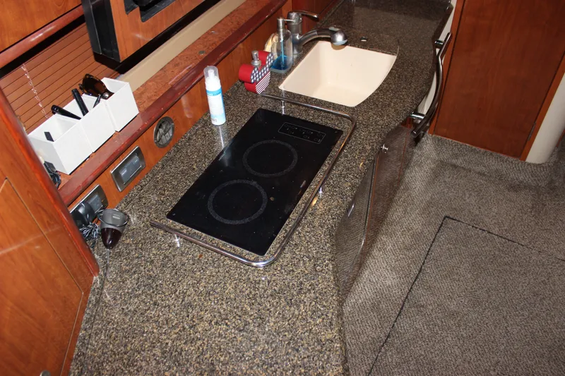 Slide: The Image of 2006 Sea Ray 40 Sundancer galley with granite countertop, sink, and electric cooktop. - 23