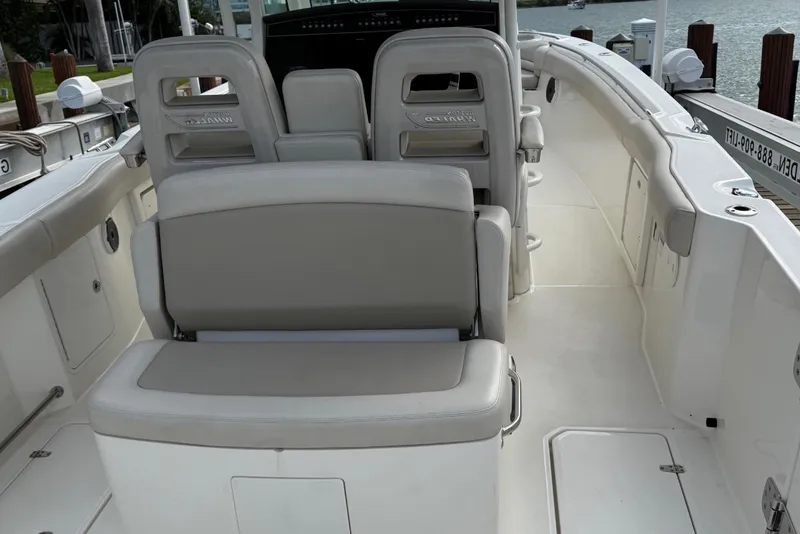 Slide: The Image of 2020 Boston Whaler 330 Outrage boat interior with seating and helm, docked by the water. - 15