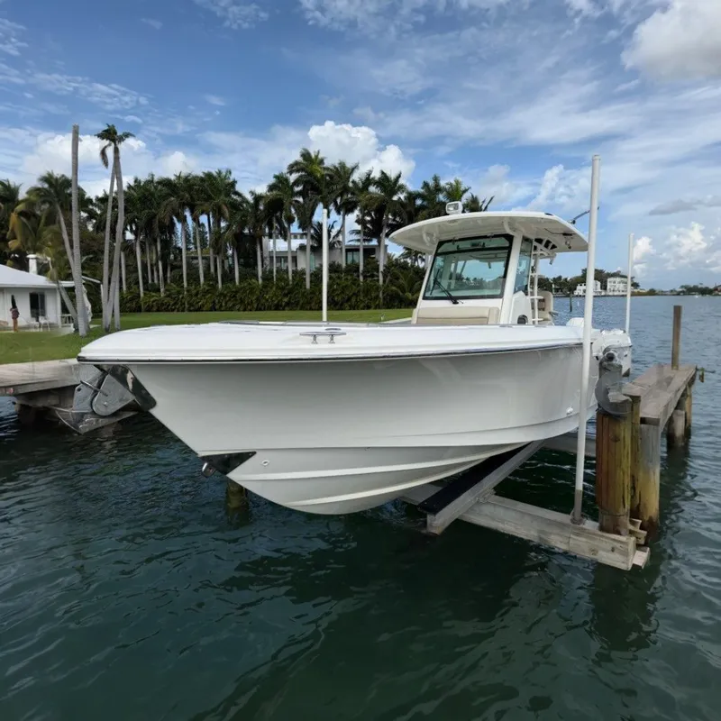 The Image of 2020 Boston Whaler 330 Outrage boat docked near palm trees and waterfront homes. - 0