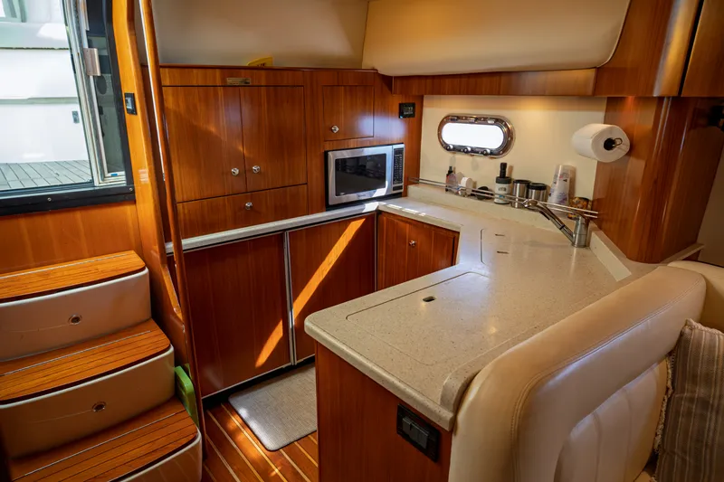 Slide: The Image of The galley of a 2006 Tiara Yachts 4400 Sovran with wooden cabinets and a small window. - 32