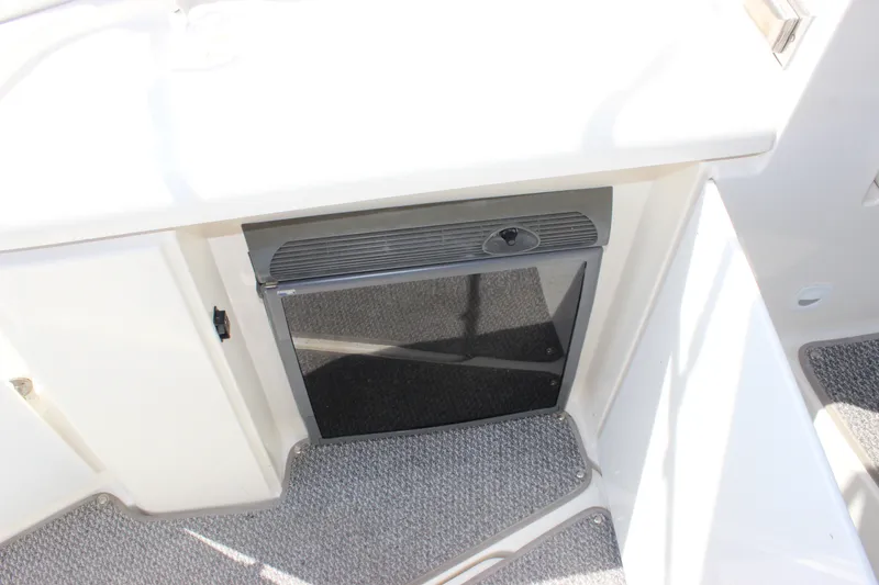 Slide: The Image of 2007 Cruisers Yachts 340 Express interior with compact refrigerator and carpeted flooring. - 24