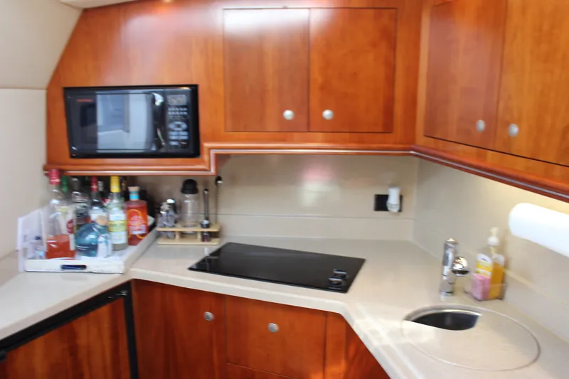 Slide: The Image of 2007 Cruisers Yachts 340 Express kitchen with microwave, stove, and wooden cabinets. - 30