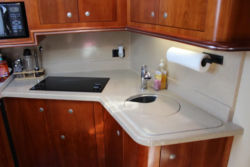 Slide: The Image of Luxurious 2007 Cruisers Yachts 340 Express kitchen with sleek countertops and wooden cabinetry. - 31