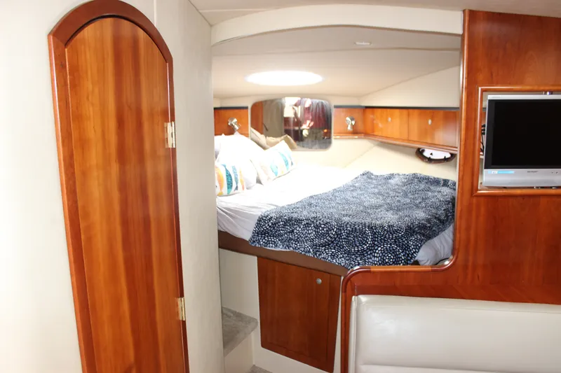 Slide: The Image of 2007 Cruisers Yachts 340 Express cabin interior with bed, wood finish, and TV. - 33