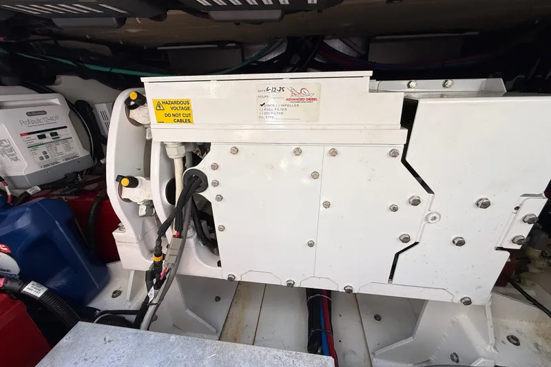Slide: The Image of Engine compartment of a 2017 Boston Whaler 420 Outrage with visible machinery and warning labels. - 52